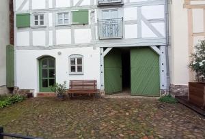 a white building with green doors and a bench at Brezelhaus in Tangermünde