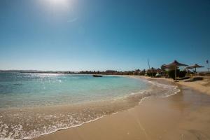 a beach with the ocean and umbrellas on it at Shams Alam Beach Resort in Abū Ghuşūn