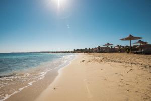 a sandy beach with umbrellas and the ocean at Shams Alam Beach Resort in Abū Ghuşūn