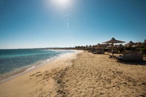 a beach with umbrellas and chairs and the ocean at Shams Alam Beach Resort in Abū Ghuşūn