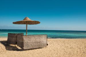 a straw umbrella on a beach with the ocean at Shams Alam Beach Resort in Abū Ghuşūn