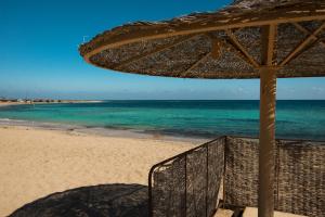 a beach with an umbrella and the ocean at Shams Alam Beach Resort in Abū Ghuşūn