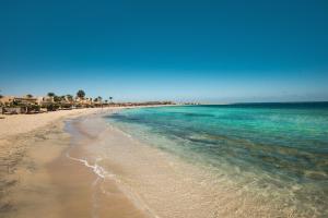 a beach with turquoise water and many umbrellas at Shams Alam Beach Resort in Abū Ghuşūn