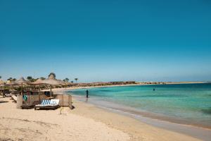 a beach with chairs and umbrellas and the ocean at Shams Alam Beach Resort in Abū Ghuşūn