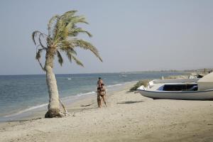 a man standing on a beach next to a boat at Shams Alam Beach Resort in Abū Ghuşūn