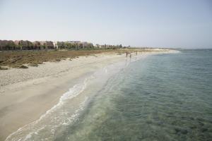 two people walking on the beach near the water at Shams Alam Beach Resort in Abū Ghuşūn