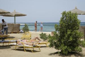 two people laying in lawn chairs on the beach at Shams Alam Beach Resort in Abū Ghuşūn