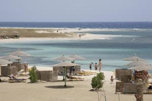 a beach with umbrellas and people on the beach at Shams Alam Beach Resort in Abū Ghuşūn