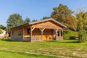 a log cabin with a porch on a lawn at Vakantiehuis De Schaapskooi in Drunen