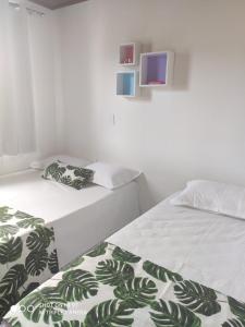 two beds in a room with a tv on the wall at Casas Bérgamo in Morro de São Paulo