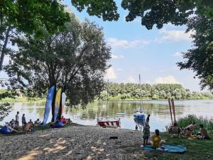 un grupo de personas sentadas en la orilla de un lago en MARINASURF Baza Wypoczynkowa, en Przeczyce