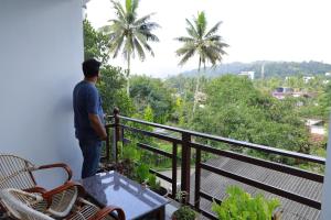 a man standing on a balcony looking out at the jungle at Periyar Woods in Thekkady