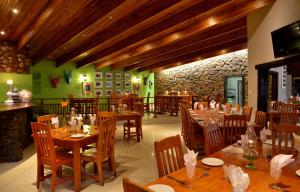 un restaurante con mesas y sillas de madera y una pared de piedra. en eBundu Lodge, en White River