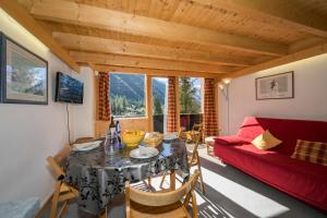 ein Wohnzimmer mit einem Tisch und einem roten Sofa in der Unterkunft Résidence Grand Roc - Ancolies 213 - Happy Rentals in Chamonix-Mont-Blanc