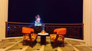 a balcony with two chairs and a table and a statue at ShriGo Hotel Nathdwara in Nāthdwāra