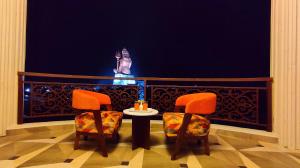 a balcony with two chairs and a table and a statue at ShriGo Hotel Nathdwara in Nāthdwāra