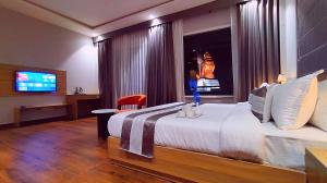 ein Hotelzimmer mit einem großen Bett und einem TV in der Unterkunft ShriGo Hotel Nathdwara in Nāthdwāra