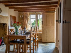 jadalnia z drewnianym stołem i krzesłami w obiekcie Honeysuckle Cottage w mieście Blockley