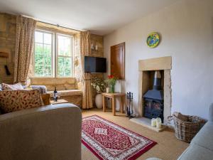 uma sala de estar com um sofá e uma lareira em Honeysuckle Cottage em Blockley