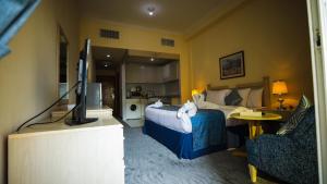 ドバイにあるGreen House Hotel Suites & Apartmentのベッドとテレビがあるホテルの部屋