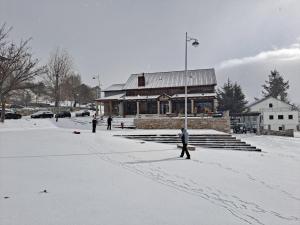 a group of people walking in the snow in front of a building at Alojamento de montanha in Penhas da Saúde