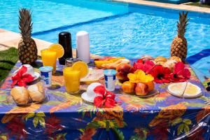 uma mesa com comida e bebidas junto a uma piscina em Pousada & Food 3 Abelhas em Cumbuco
