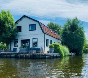 a house sitting on a dock on a river at Holiday home at the water, fire place, boat and SUP rent, near Amsterdam in Aalsmeer