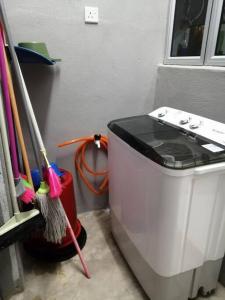 a washing machine sitting next to a pile of cleaning brushes at HOMESTAY KUANTAN INDERA SEMPURNA 2 in Kuantan