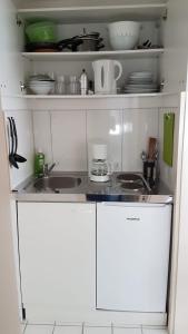 a small kitchen with white cabinets and a sink at Ferien- und Businessapartment I Modern mit WLAN und Parkplatz nahe Zentrum, Automobil- und Tech-Firmen, Messe in Renningen +6 photos