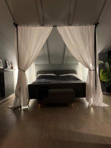 een slaapkamer met een bed met gordijnen en een bank bij La Vista Barolo in La Morra in La Morra