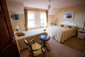 a bedroom with two beds and a table and a chair at Seashore B&B in Ballybunion