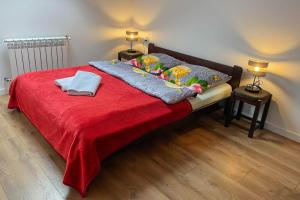 a bedroom with a bed with a red blanket and two lamps at Apartament Bieszczady in Hoczew