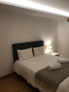 Un dormitorio con una cama grande con sábanas blancas. en Alojamento de montanha, en Penhas da Saúde