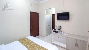 a bedroom with a bed and a tv on the wall at Atmosfer Guest House Sentul in Bogor