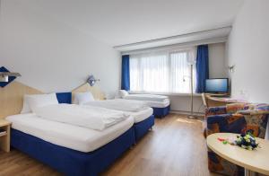 a hotel room with two beds and a television at Hotel Blumenstein Self-Check In in Frauenfeld