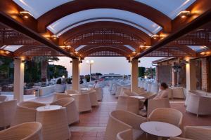 a restaurant with white chairs and tables and a ceiling at Bella Beach Hotel in Hersonissos