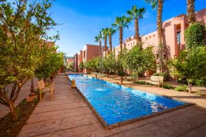 - une piscine dans une cour avec des palmiers et des bâtiments dans l'établissement Hapimag Resort Marrakesh, à Douar Soukkane