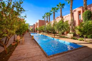 a swimming pool in a courtyard with palm trees and buildings at Hapimag Resort Marrakesh in Douar Soukkane