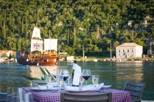 a table with wine glasses and a boat in the water at BoGo-Galijun in Dubrovnik