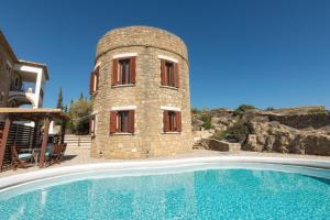 a building with a swimming pool next to a house at Armonia Seaside Villas in Vasilikos