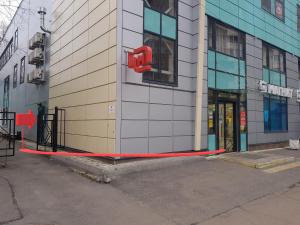 a building with a red sign on the side of it at Happy Inn Hotel Alpiyskiy in Saint Petersburg