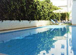 a swimming pool with two chairs and an umbrella at Apollon Hotel in Agios Nikolaos