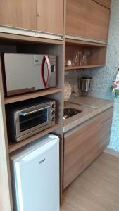 a small kitchen with a microwave and a refrigerator at Flat Vista Azul Hotel in Pedra Azul