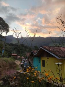 a yellow and blue house with mountains in the background at Pousada e restaurante Além das Nuvens in Guaratinguetá +17 photos