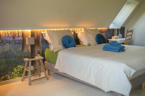 1 dormitorio con 1 cama grande con almohadas azules en B&B De Zavelaar, en Heuvelland