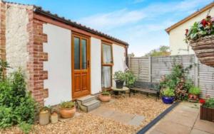 Private Detached Annex in Isleham Village في Isleham: حديقة صغيرة مع مقعد أمام المنزل