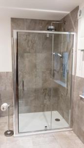 a shower with a glass door in a bathroom at Slatehouse Cottage, Drumlanrig in Thornhill