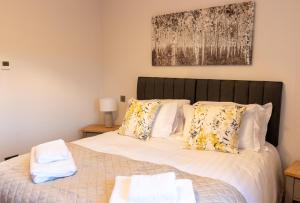 1 dormitorio con 1 cama con sábanas y almohadas blancas en Slatehouse Cottage, Drumlanrig en Thornhill