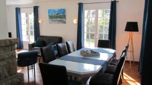 comedor con mesa, sillas y ventanas en Maison au calme grand jardin privé aire de jeux Lac de Guerledan en Plouguernével