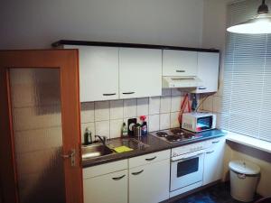 a kitchen with white cabinets and a sink and a microwave at Monteurwohnung in Nuremberg